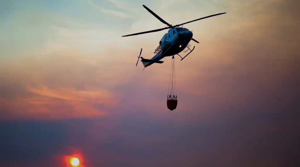 Helicopter airlifting fuel product during sunset