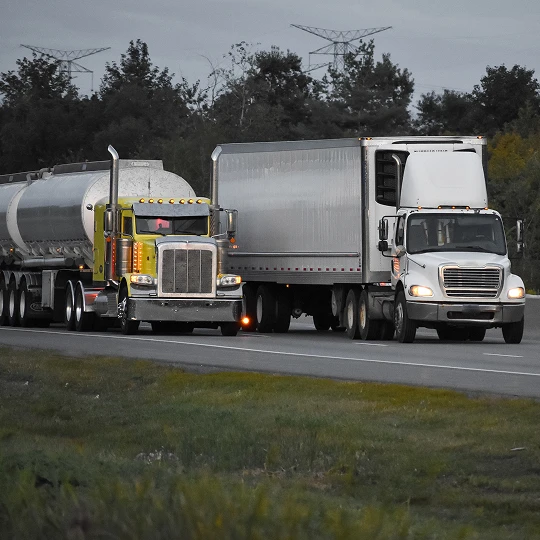 Fuel tanker and transport trucks travelling side by side on a highway.