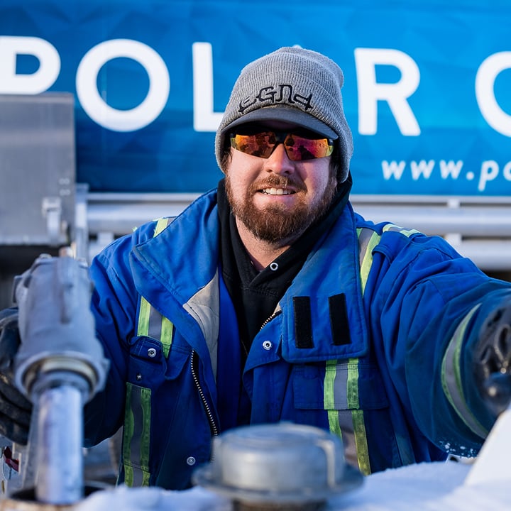 Polar Oils worker handling fuel equipment in front of a Polar Oils delivery truck.