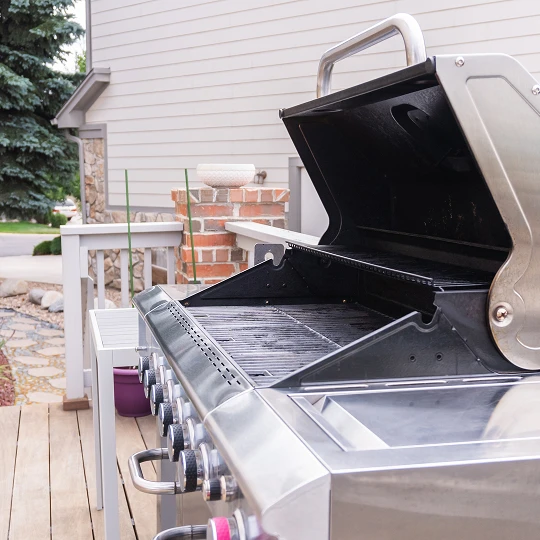 Open propane grill on wooden deck