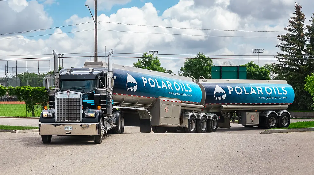 Polar Oils fuel transport truck with blue branded tanker trailers pulling into driveway outdoors